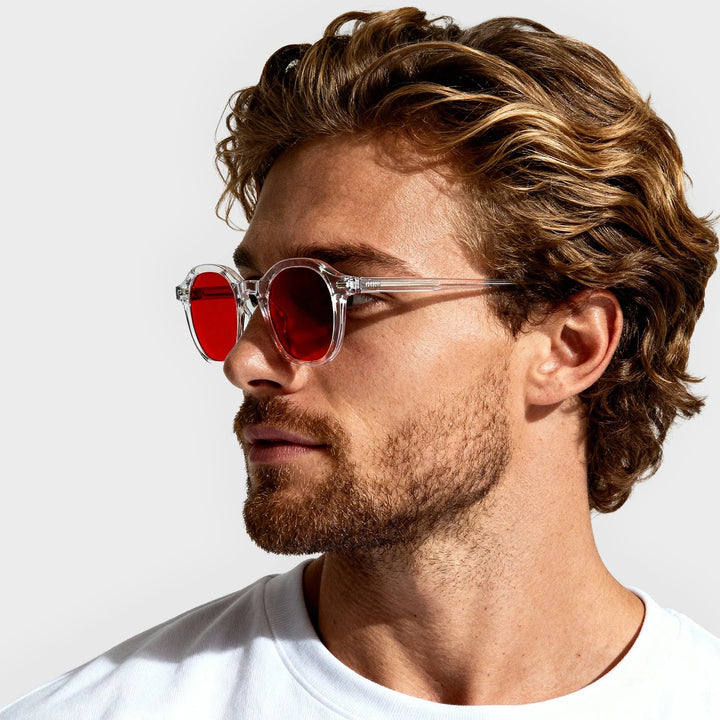 Man wearing red blue light glasses with a neutral background